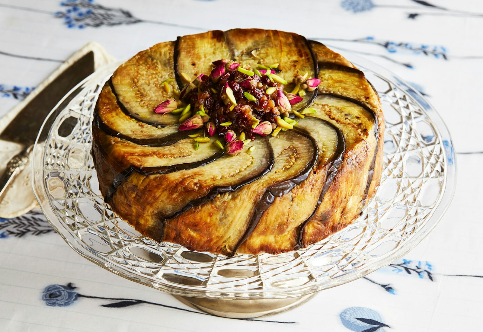Tachin with barberries, pistachios and rose buds atop glass serving tray.