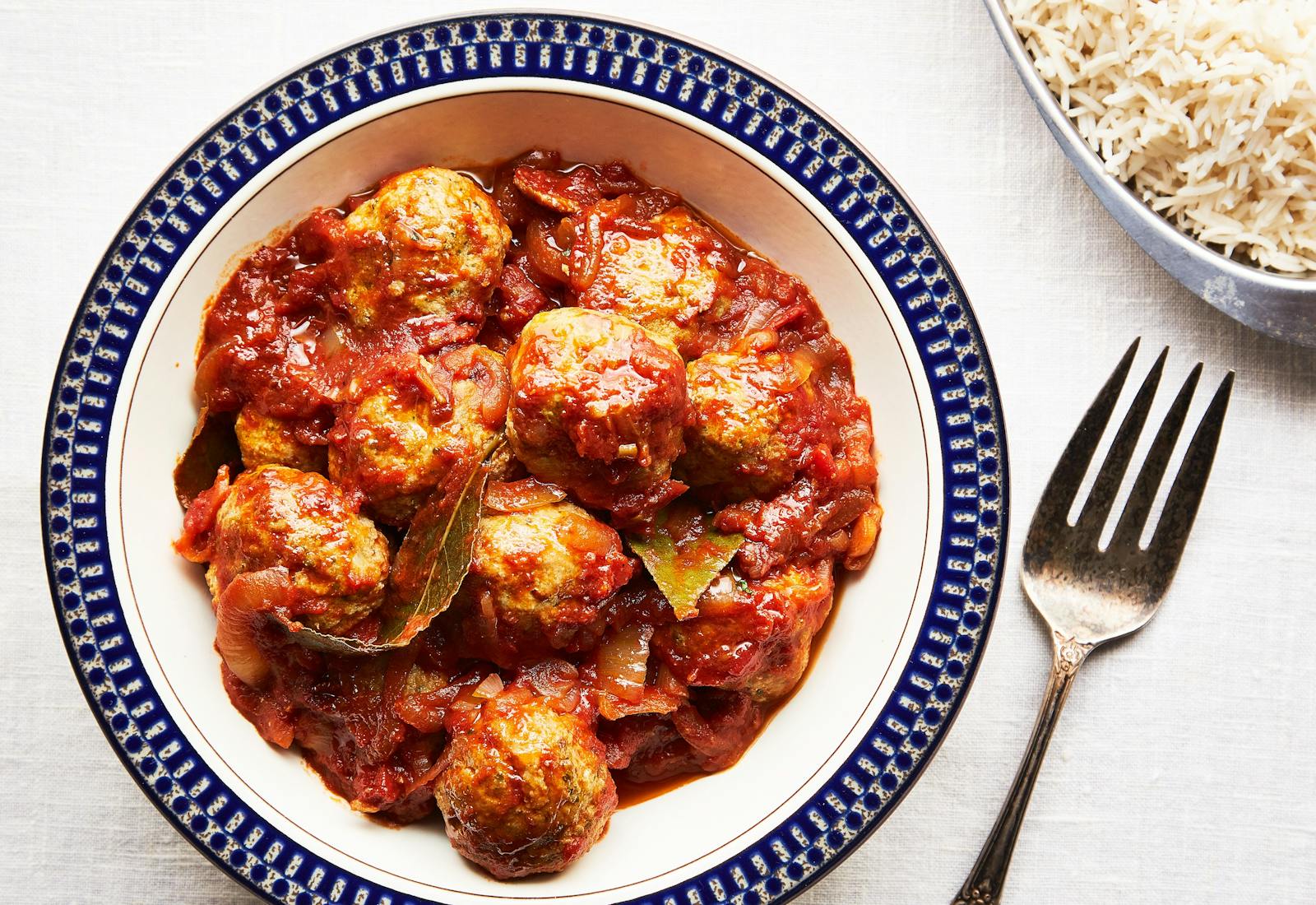 Fish balls in tomato sauce alongside white rice.