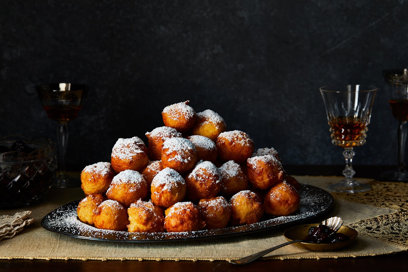 Stacked donuts on a serving platter sprinkled with powdered sugar.