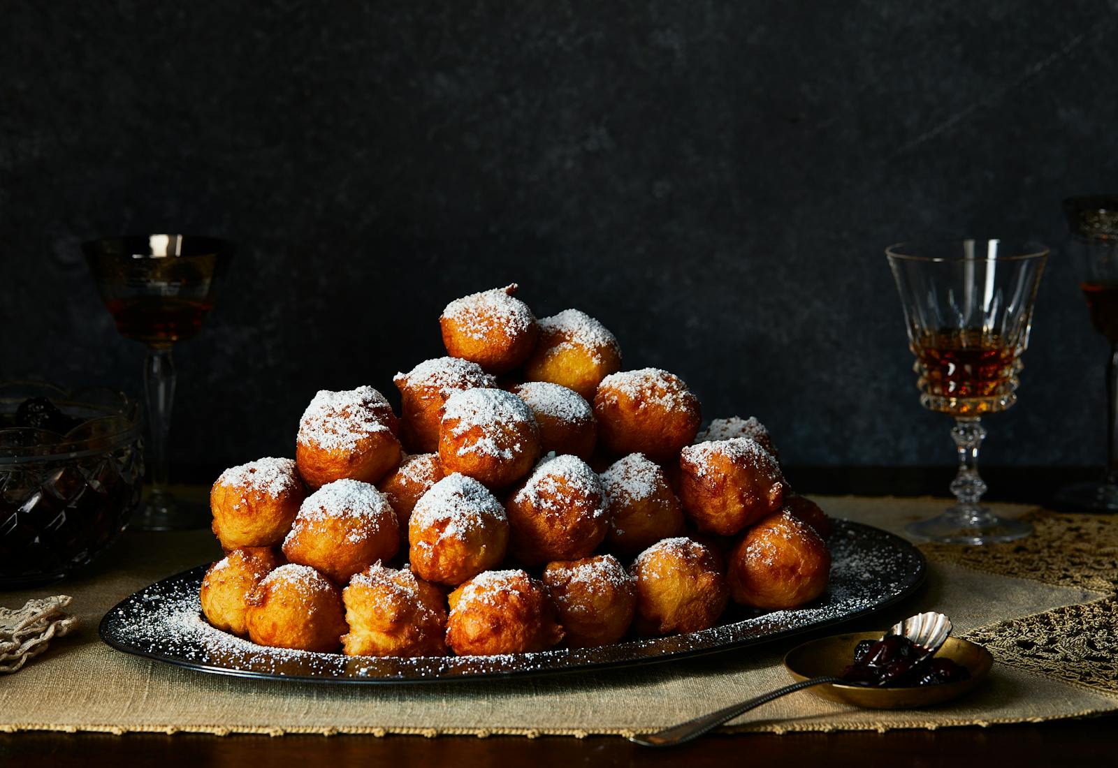 Stacked donuts on a serving platter sprinkled with powdered sugar.