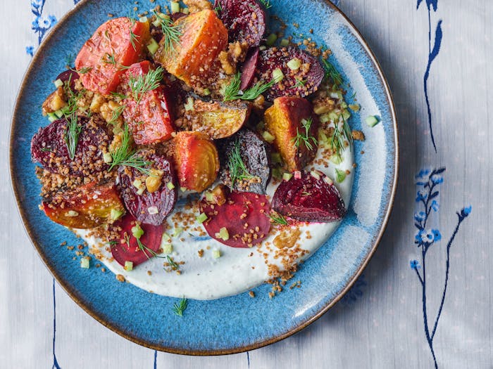 Roasted beets over horseradish yogurt in blue bowl.