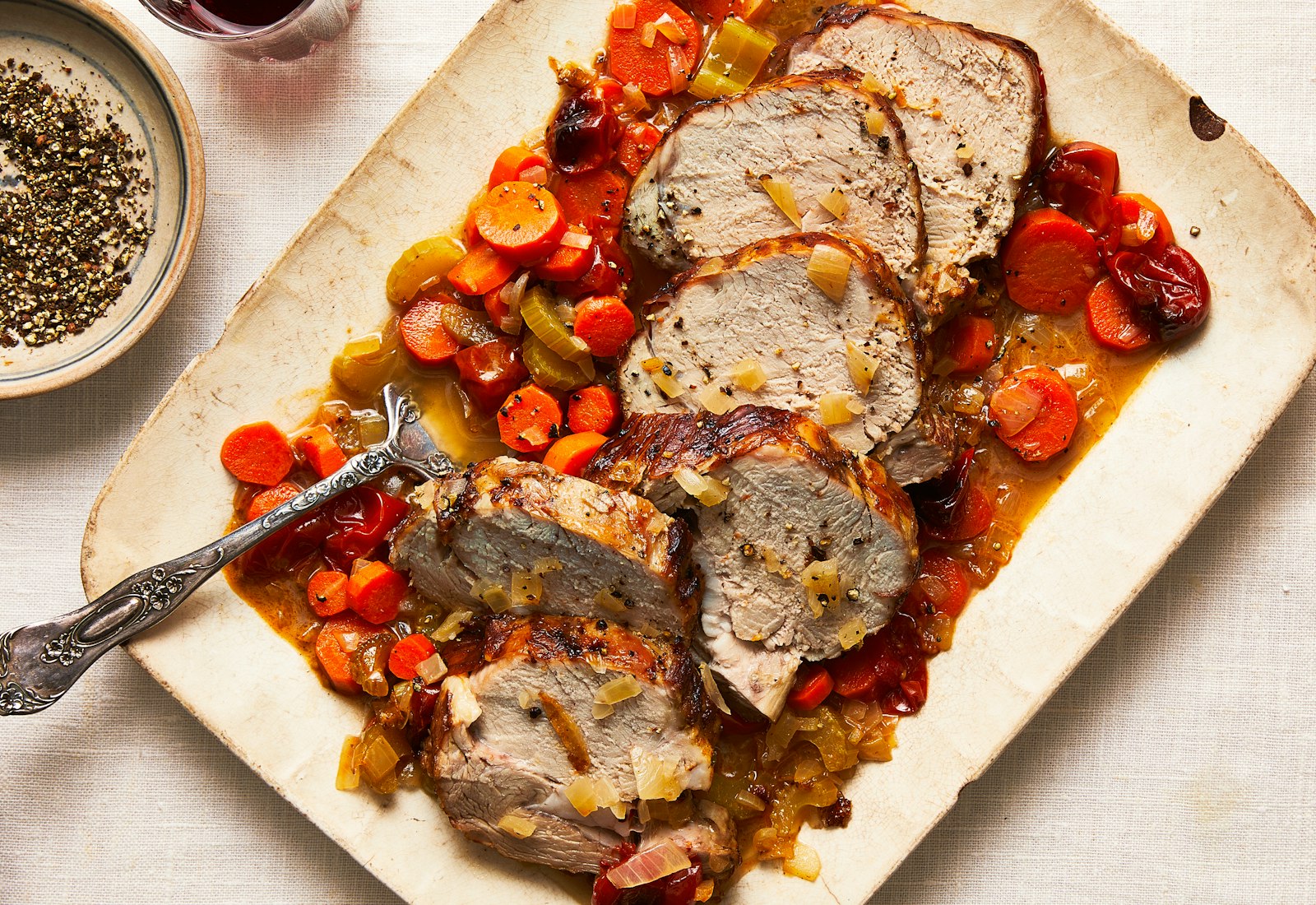 Sliced veal over wine-braised carrots, celery, onion and tomato on serving platter.