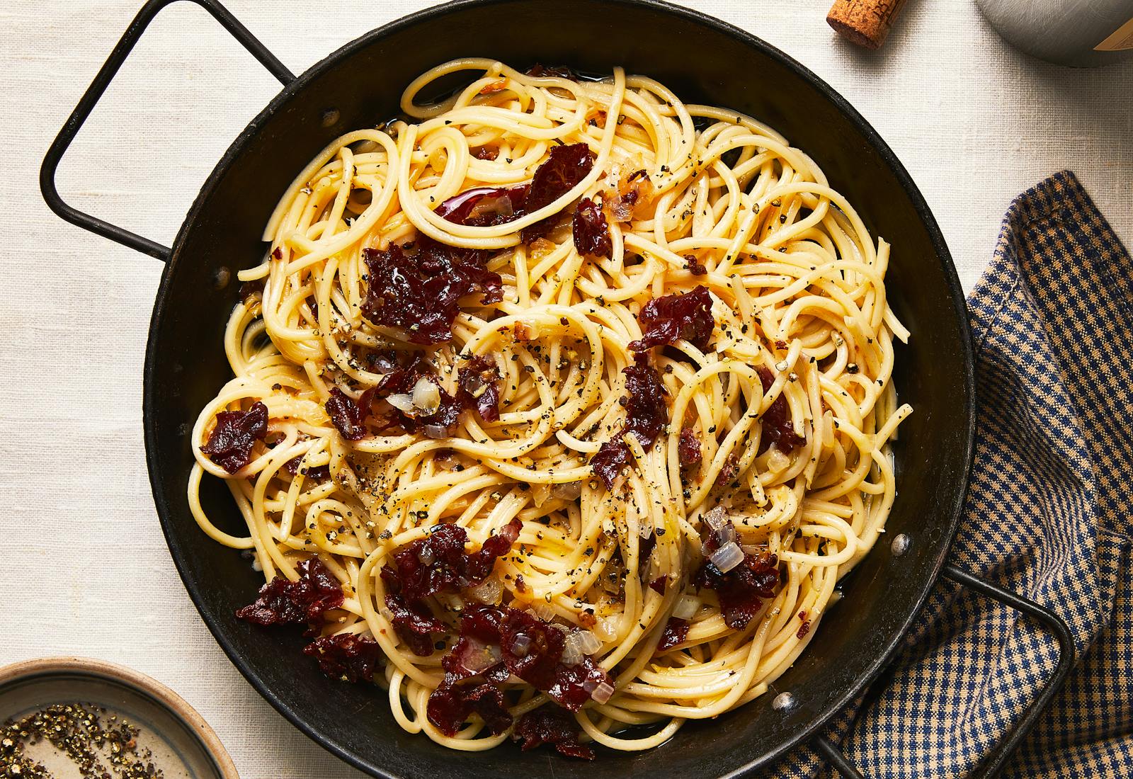Carbonara in large serving pan with a checkered napkin on the side.