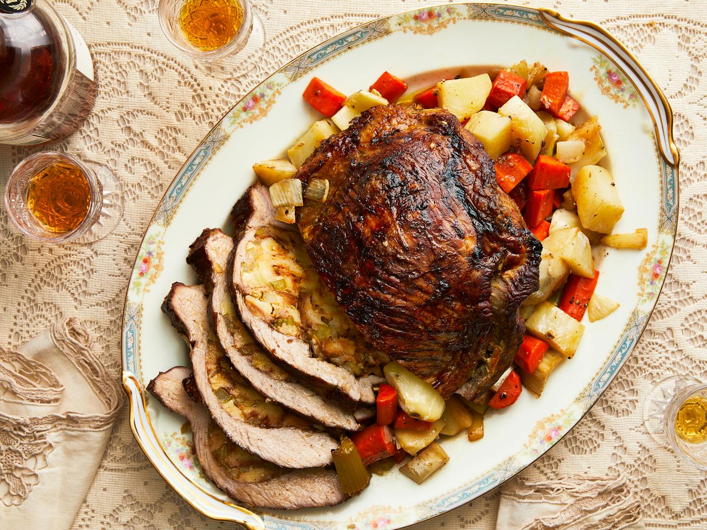 Stuffed veal with roasted vegetables, partially sliced on grandma chic serving platter with plum liquor on the side.