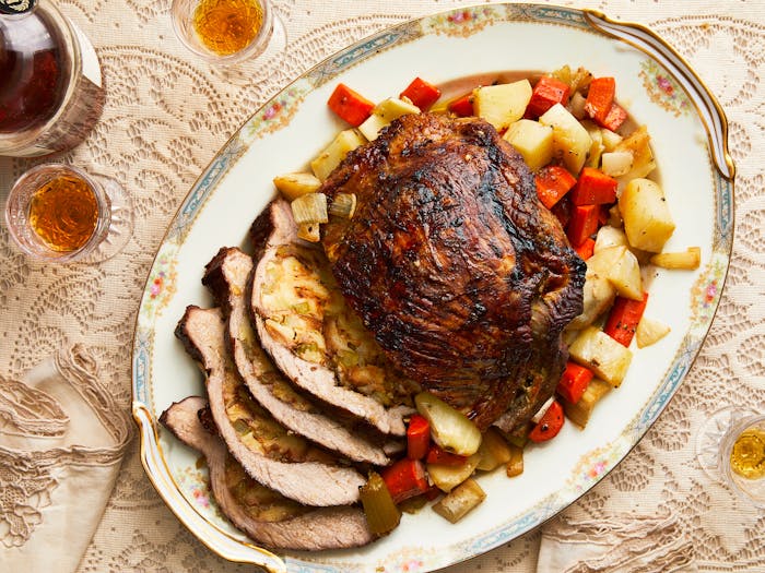 Stuffed veal with roasted vegetables, partially sliced on grandma chic serving platter with plum liquor on the side.