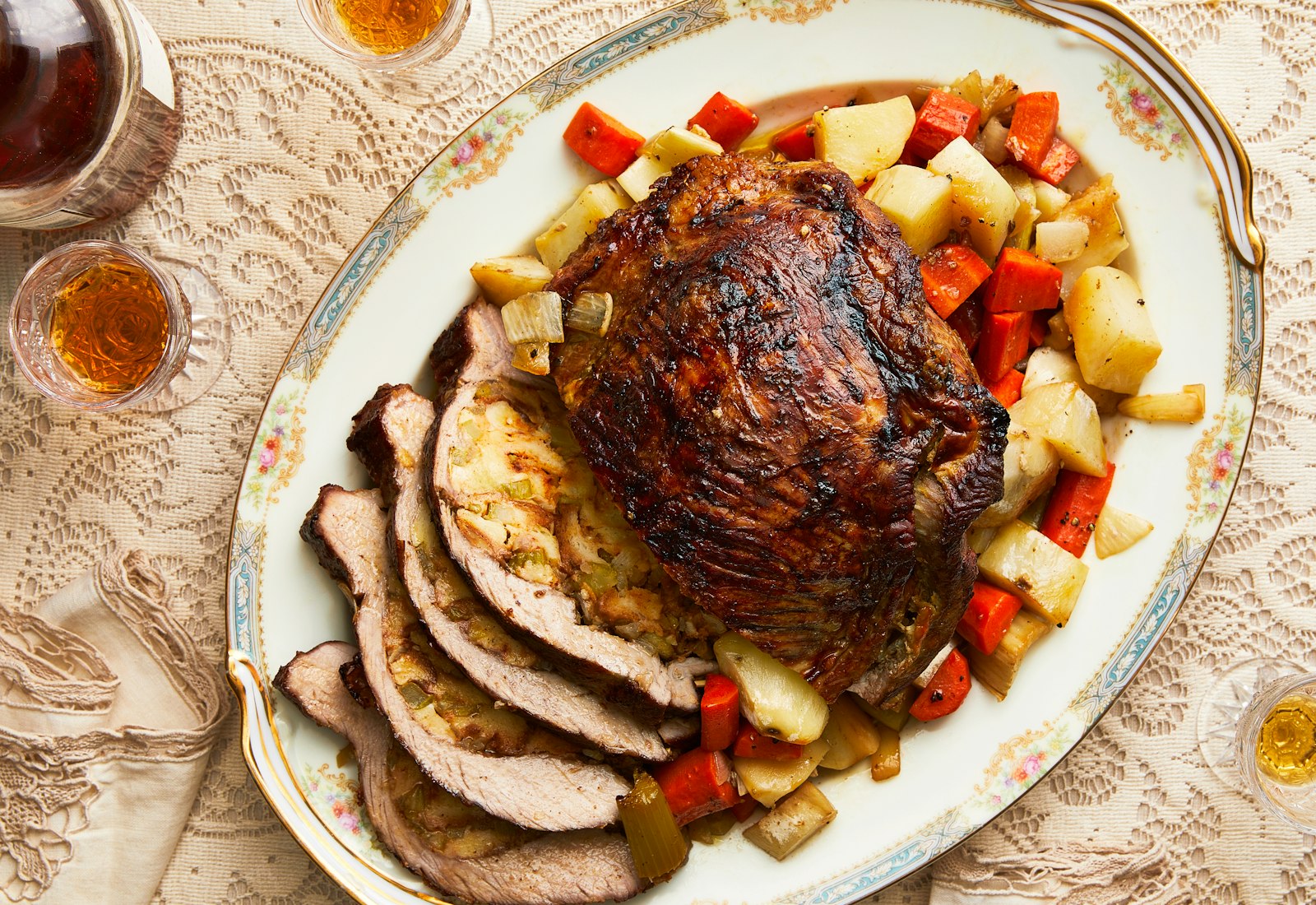 Stuffed veal with roasted vegetables, partially sliced on grandma chic serving platter with plum liquor on the side.