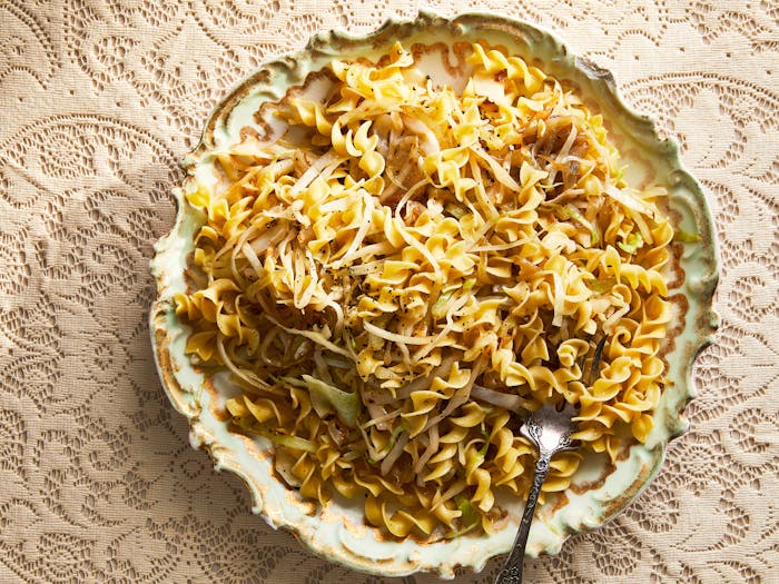 Sweet cabbage noodles in decorative serving bowl atop cream, lace tablecloth.