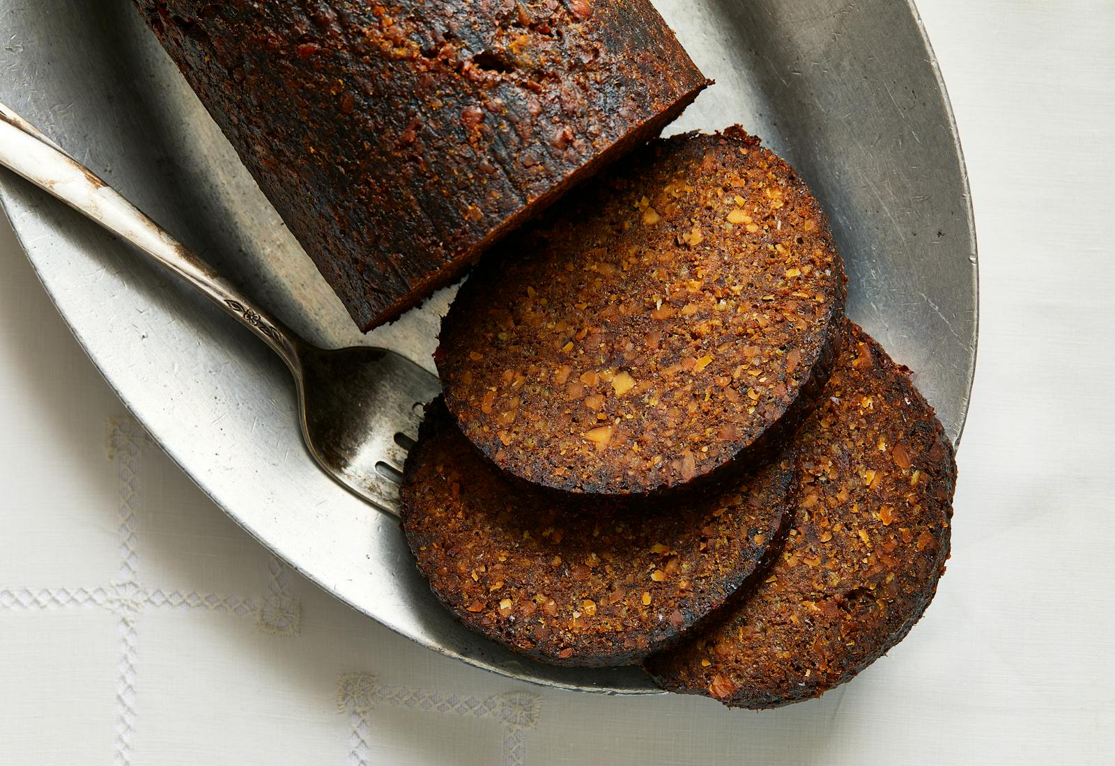 3 slices of ma'amra on oval silver platter atop white tablecloth.