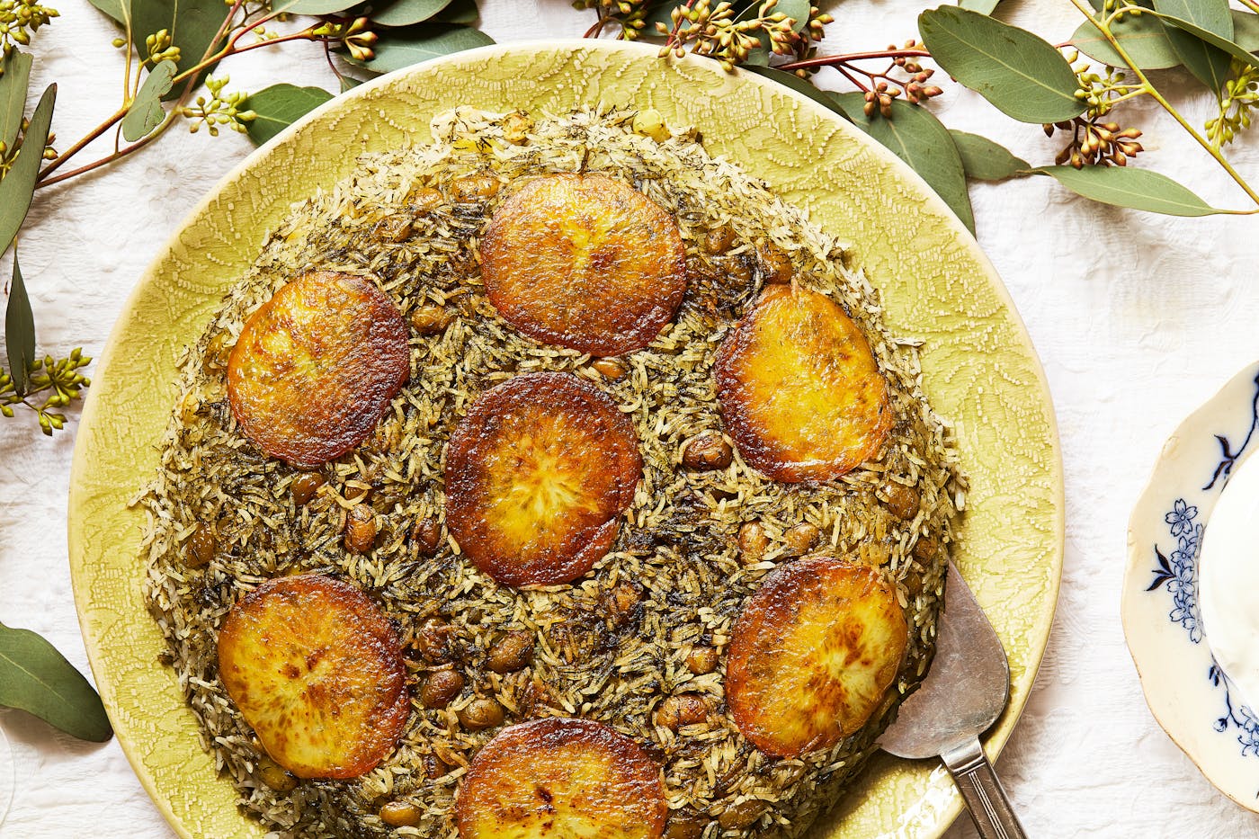 Green rice with potato tahdig on yellow serving platter.