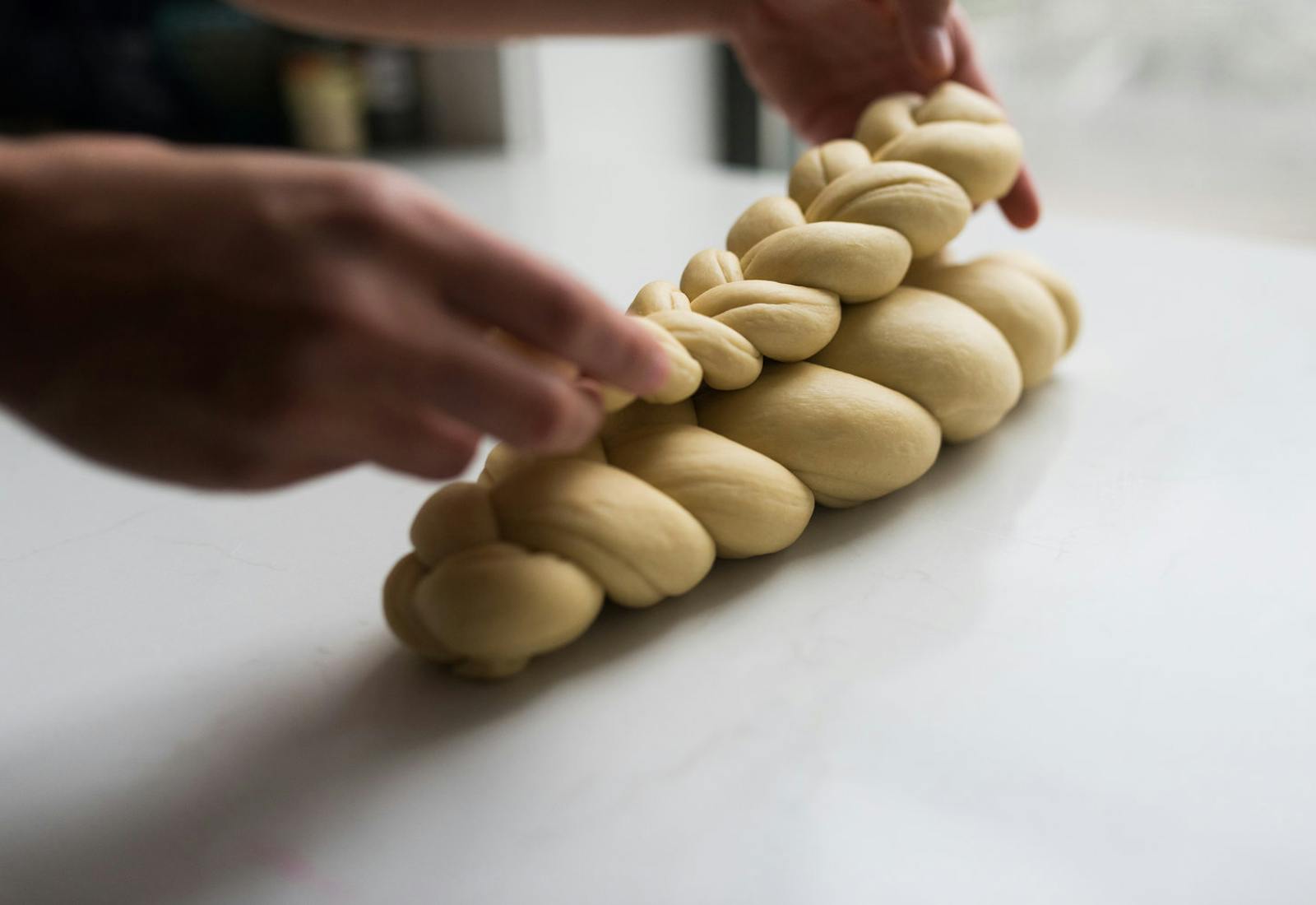Chef preparing layered challah braids to bake.