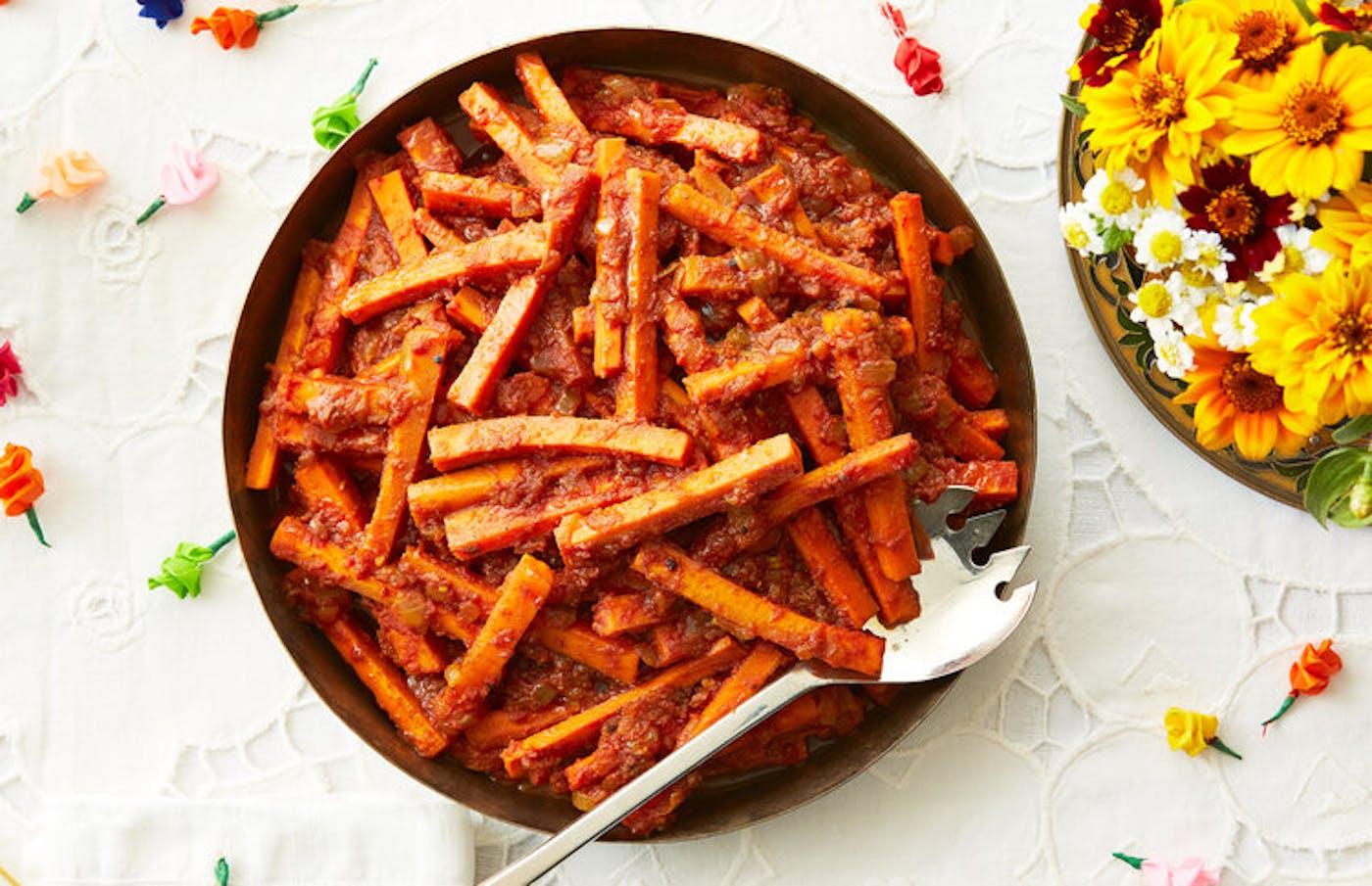 Carrots in spiced tomato paste, fresh flowers, colorful paper roses.
