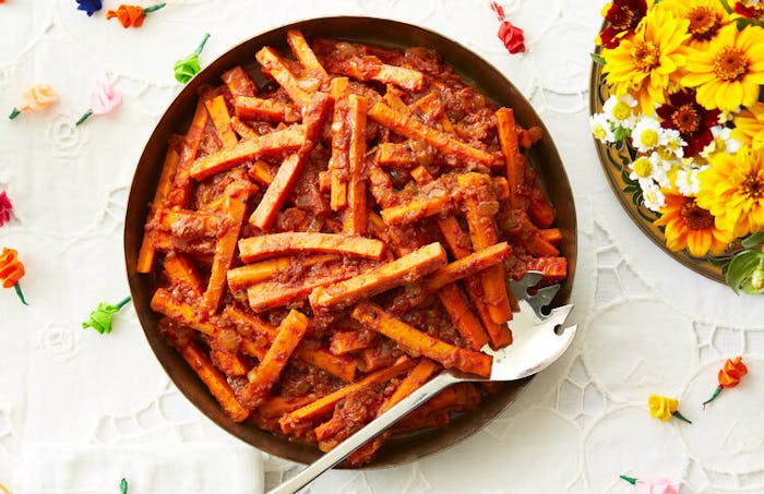 Carrots in spiced tomato paste, fresh flowers, colorful paper roses.