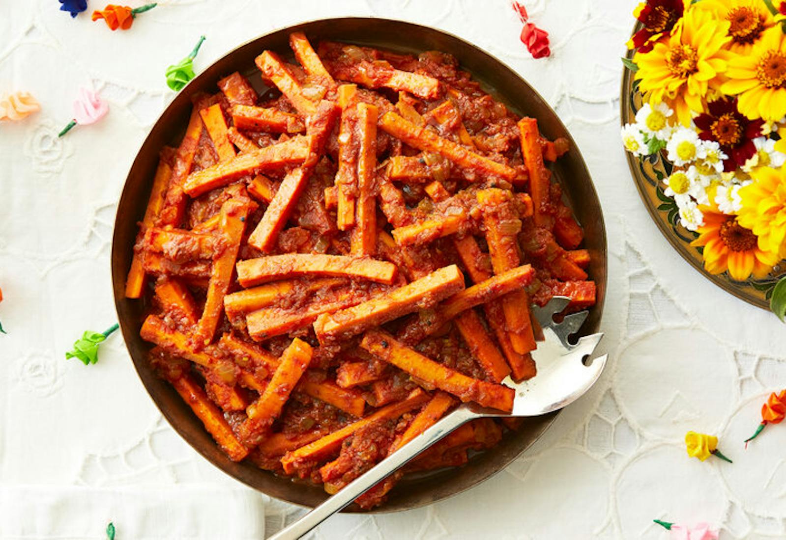 Carrots in spiced tomato paste, fresh flowers, colorful paper roses.