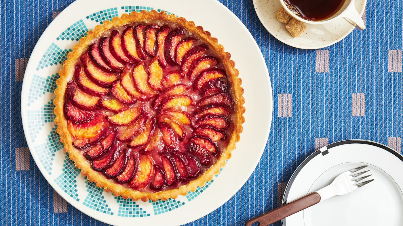 Peach tart on blue and white plate atop blue patterned tablecloth.