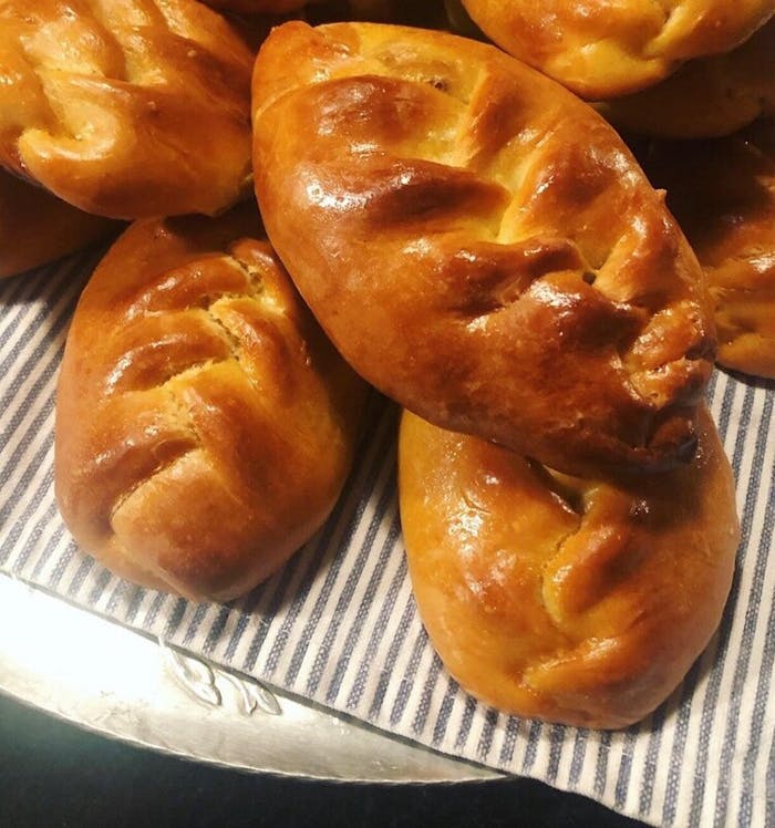 Pirozhki piled atop tablecloth.