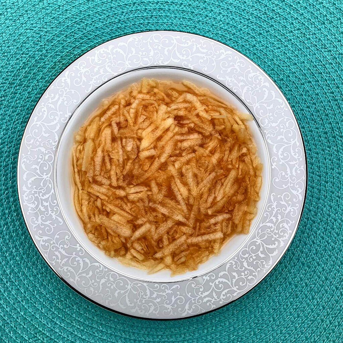 Faloodeh in grey bowl atop blue woven placemat. 