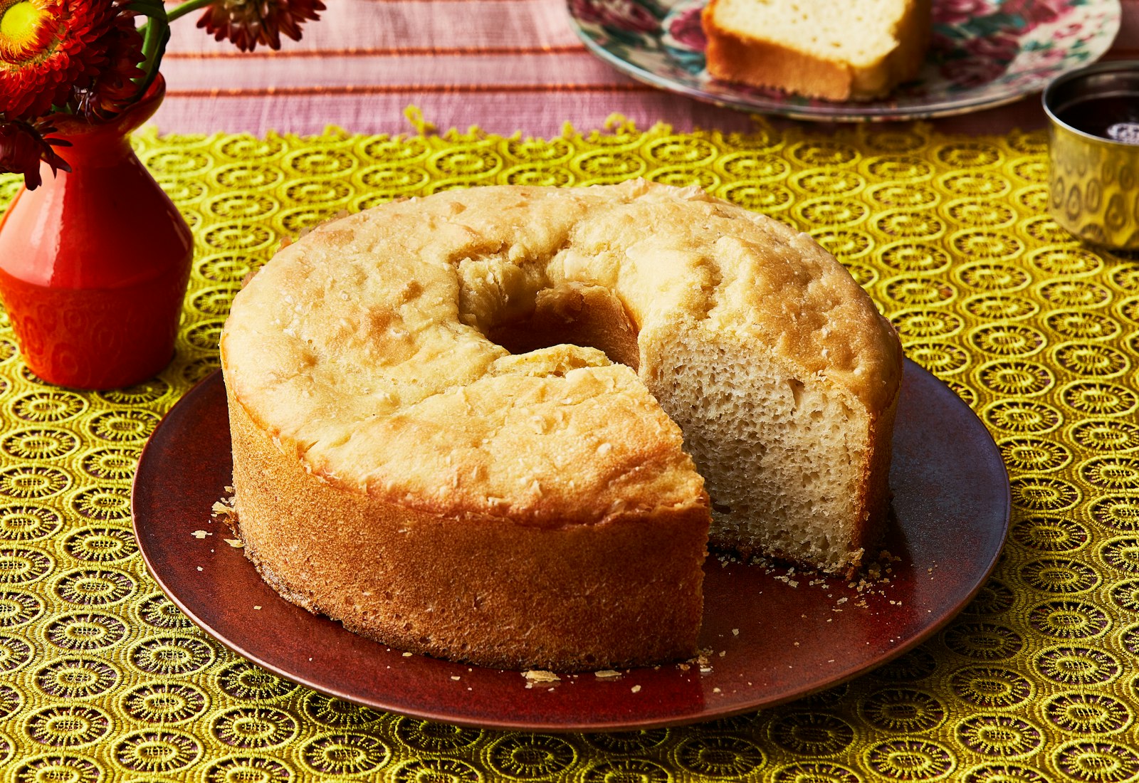 Appam on burgundy plate, over yellow embroidered tablecloth.