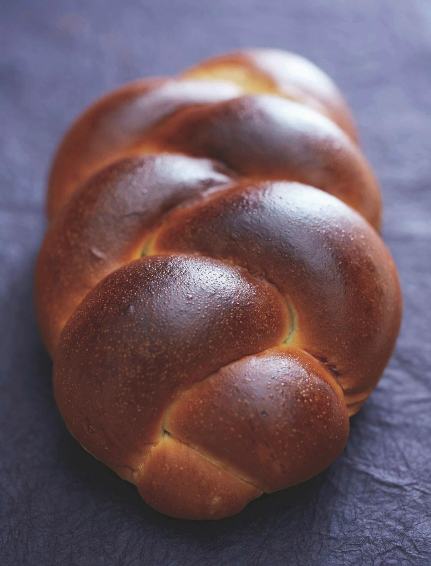 Golden braided challah atop navy tablecloth.