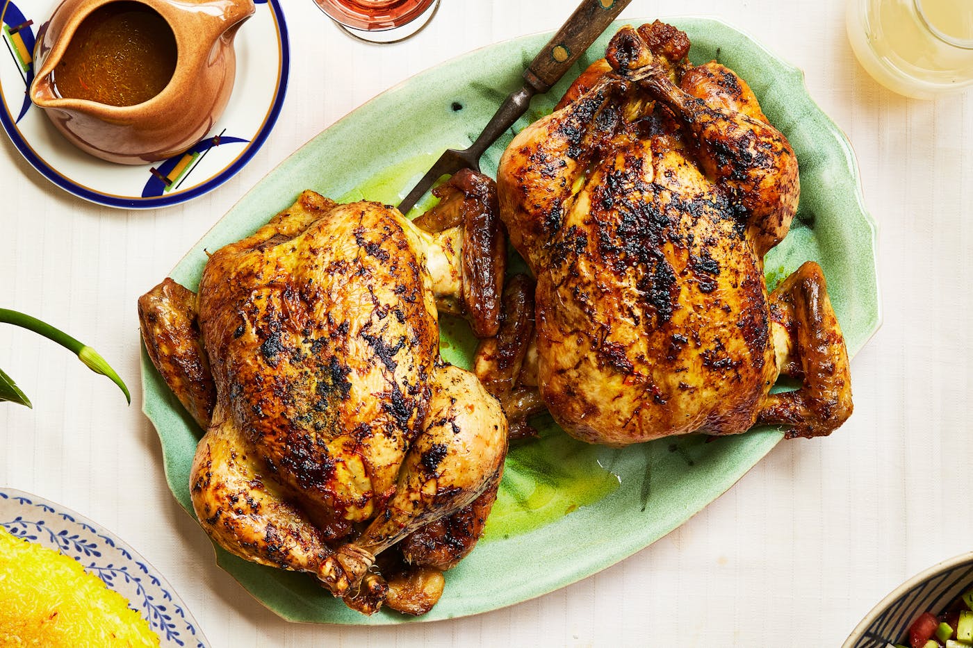 Saffron roast chicken alongside carafe of jus.