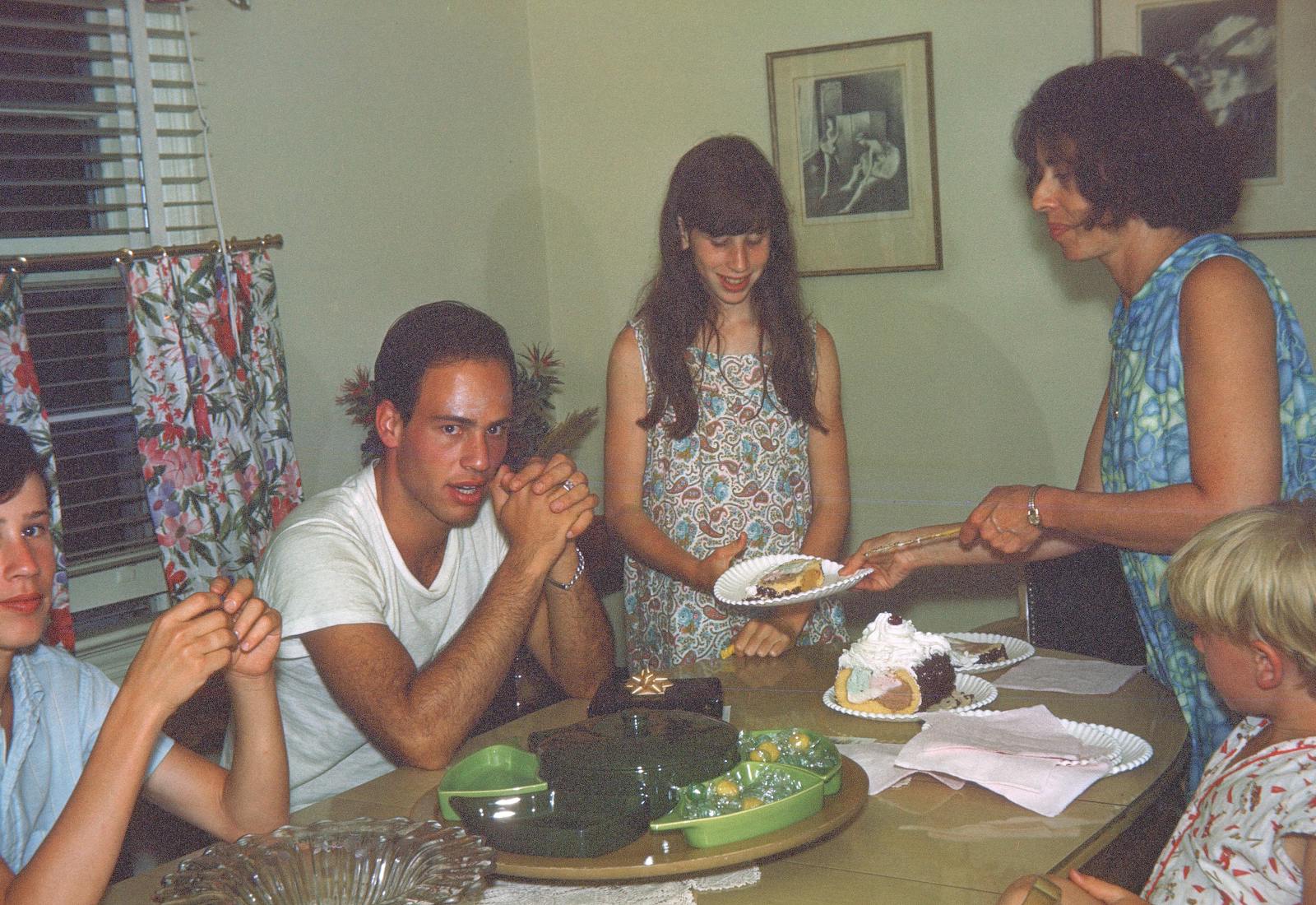 Stern siblings around dining table as mother serves ice cream cake.
