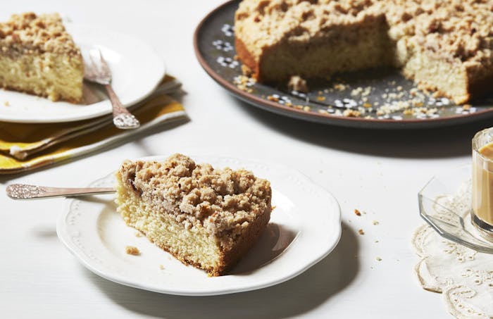 Tray of cake with two slices cut out, mug of coffee.