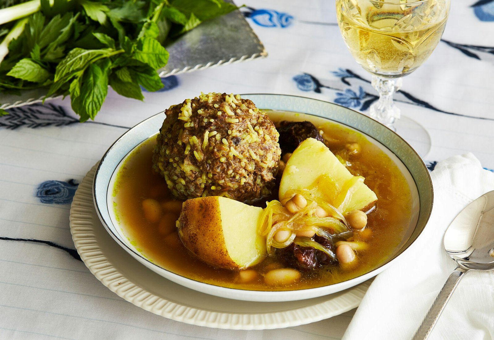 Soup in a shallow bowl with fresh herbs, scallions and white wine. 