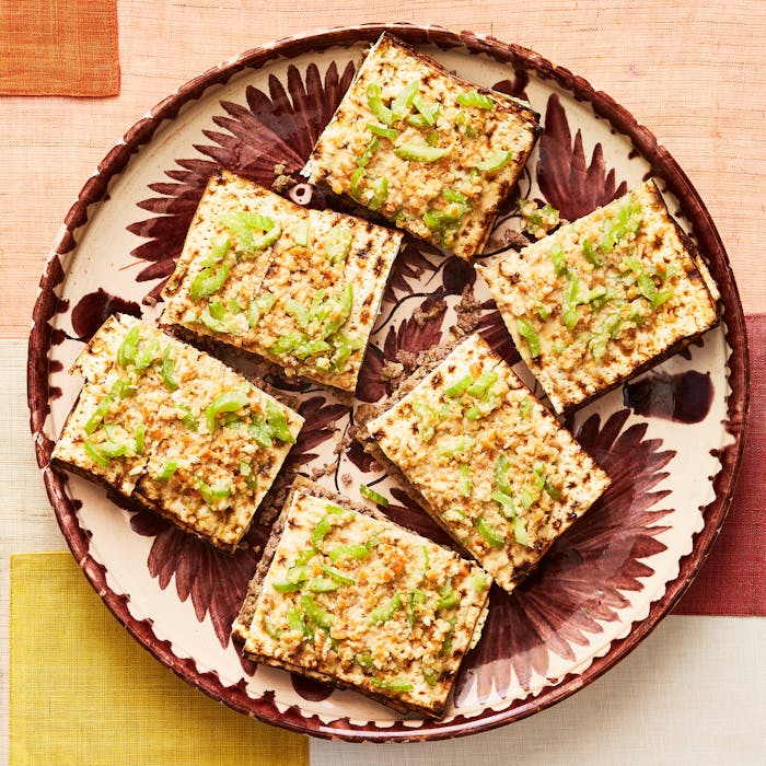 Matzo kebab on red and pink plate over patterned tablecloth.