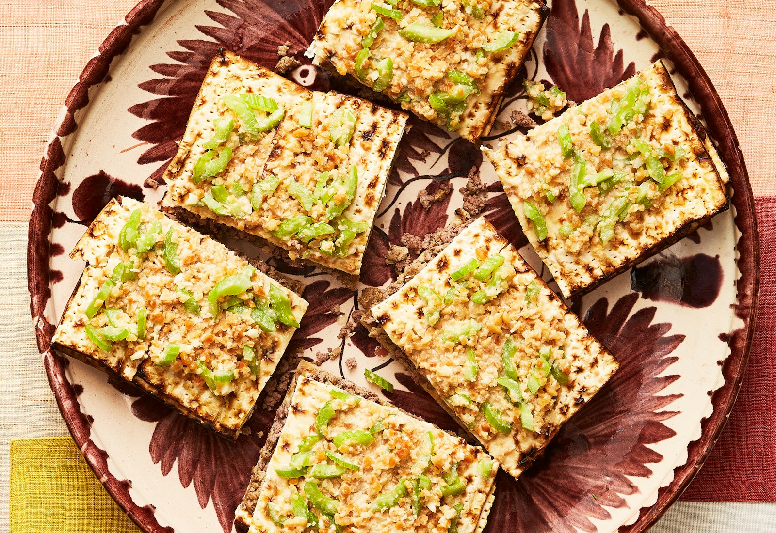 Matzo kebab on red and pink plate over patterned tablecloth.