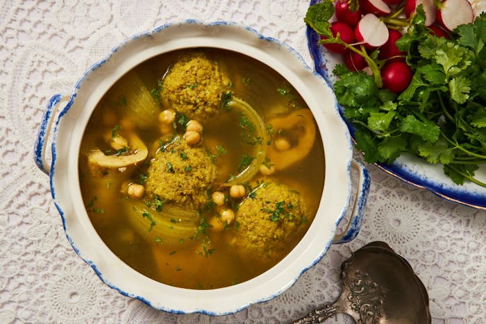 Meatball soup in dutch oven with side of cilantro and radishes.