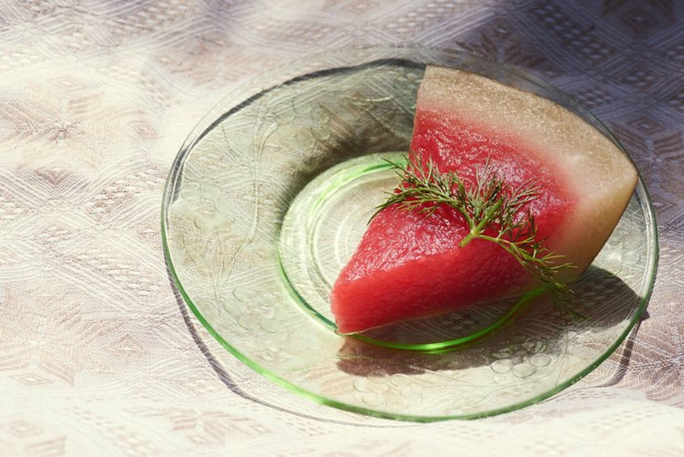 Slice of pickled watermelon with sprig of dill on top.