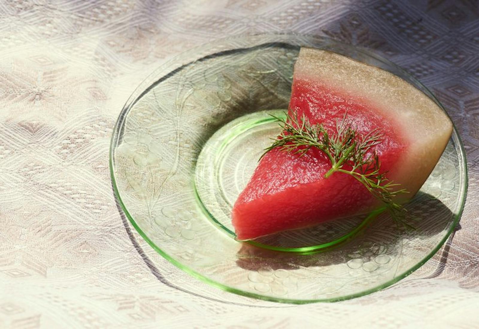 Slice of pickled watermelon with sprig of dill on top.