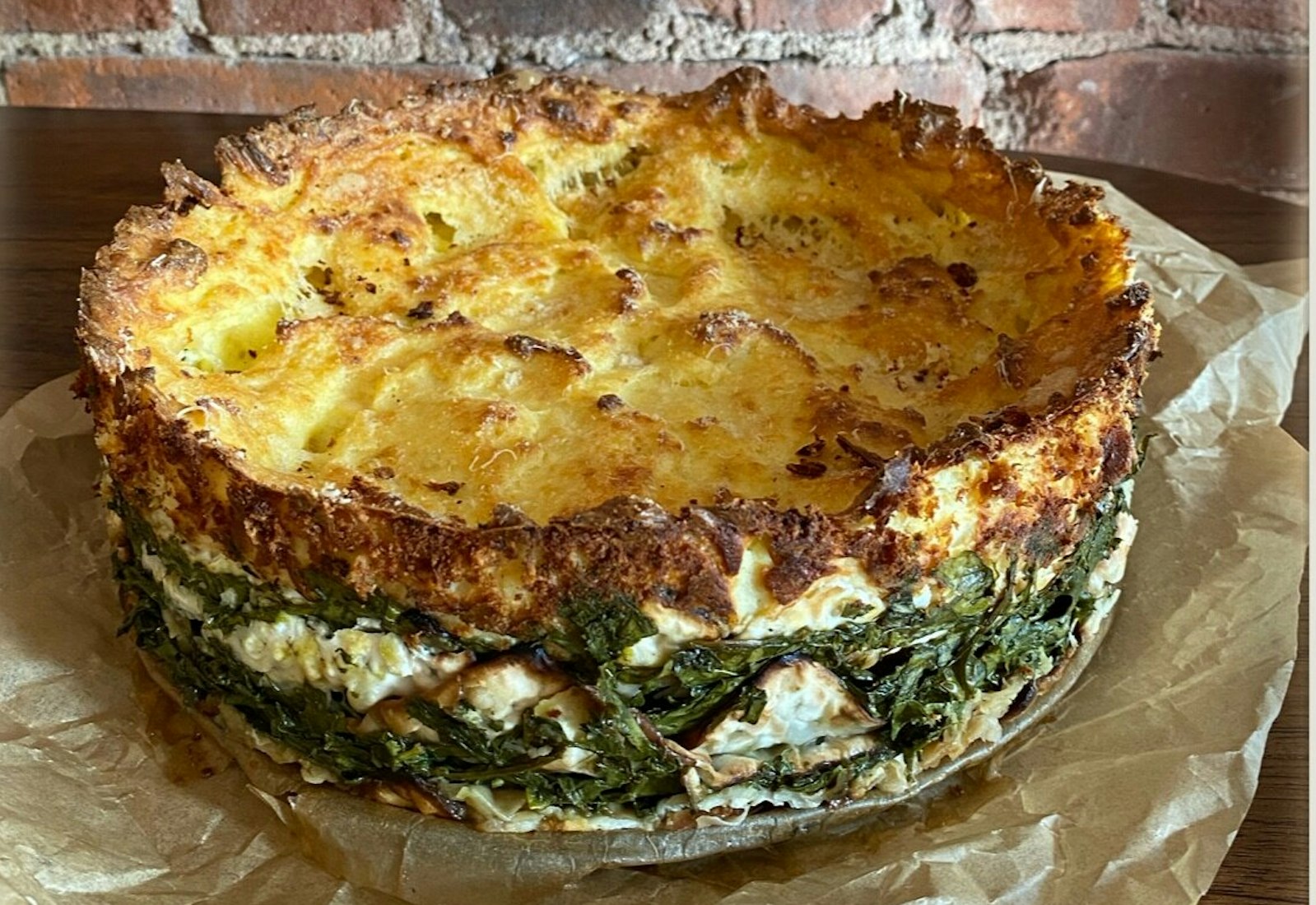 Mina on parchment paper atop wooden table, in front of brick wall.