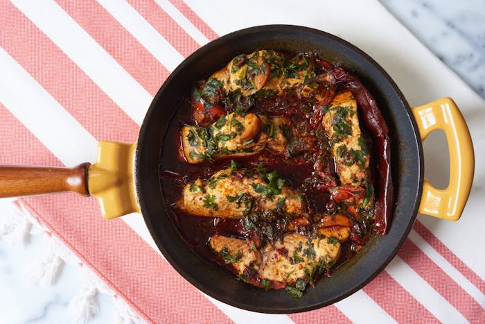 Spicy Moroccan fish in sauce with cilantro and dried guajillo peppers in cast iron skillet.