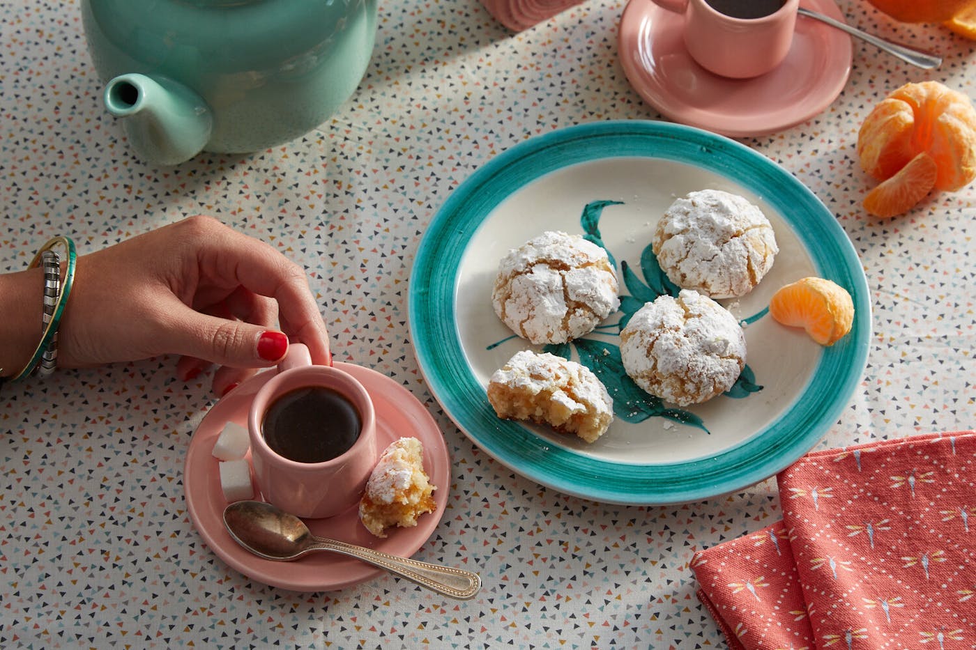 Plate of marunchinos alongside tea with sugar cubes and orange wedges.