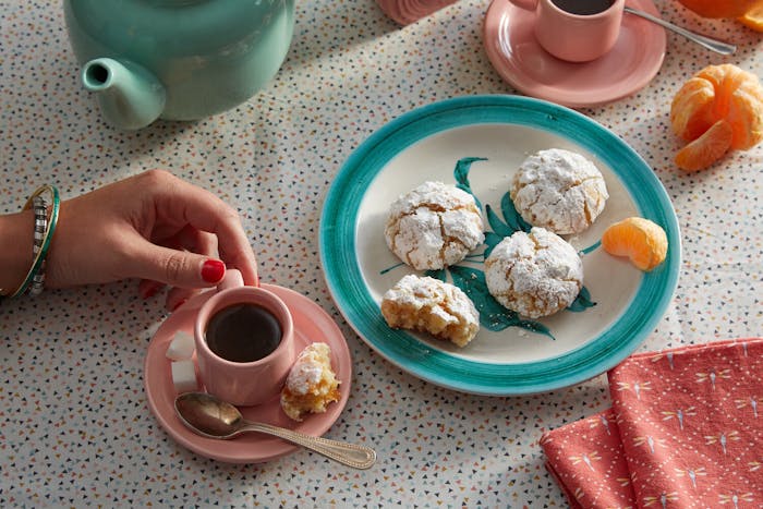 Plate of marunchinos alongside tea with sugar cubes and orange wedges.