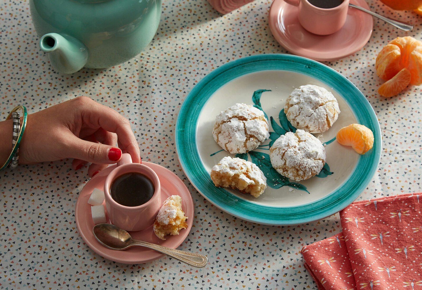 Plate of marunchinos alongside tea with sugar cubes and orange wedges.