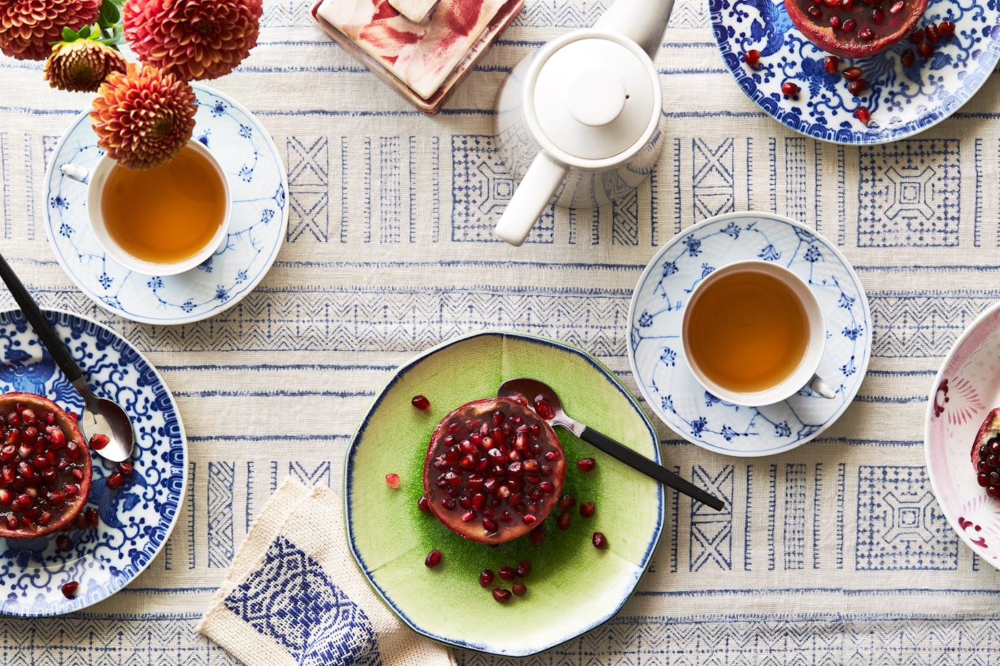 Table spread of 3 plates of pomegranate jelly atop blue and white tablecloth.