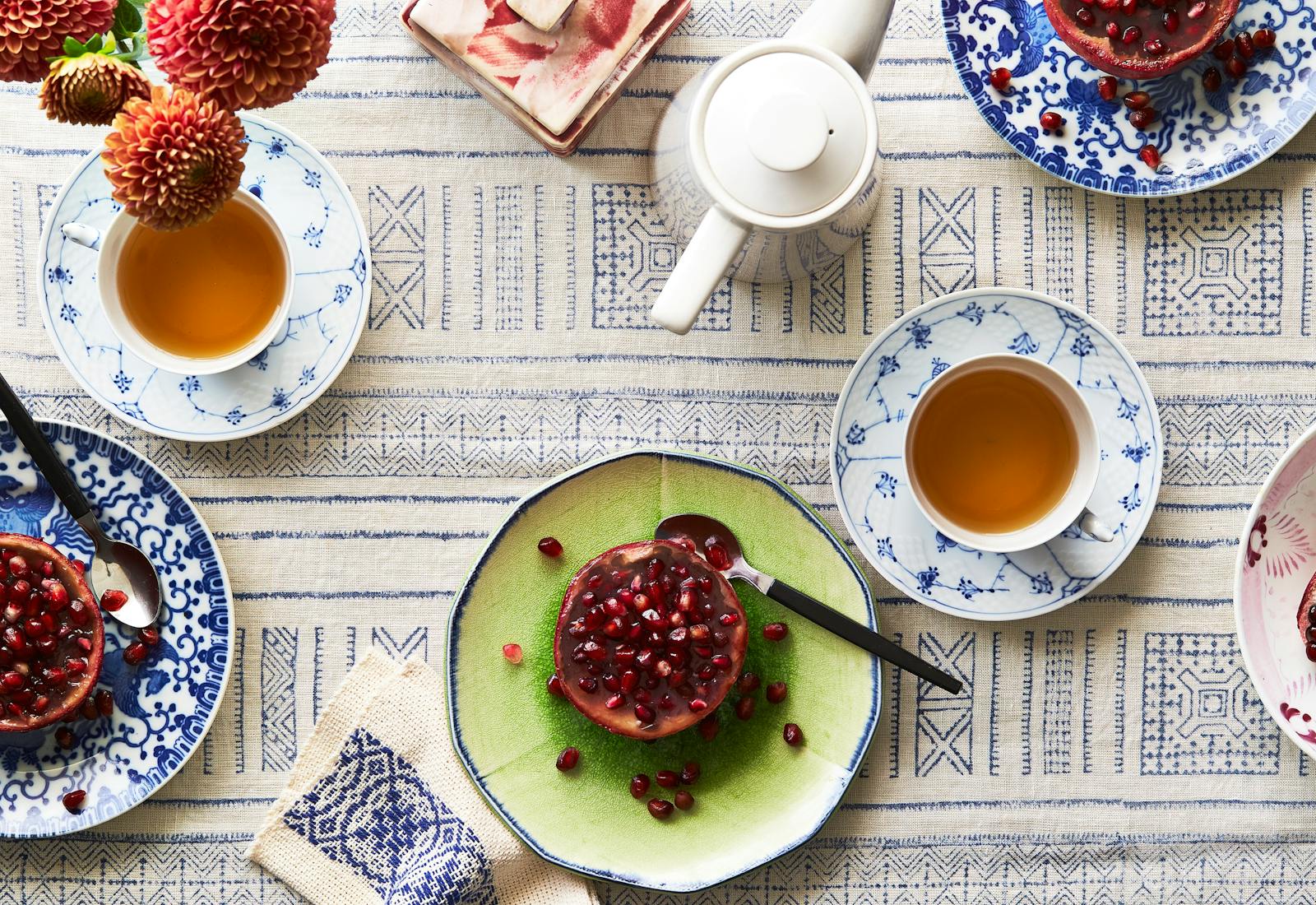 Table spread of 3 plates of pomegranate jelly atop blue and white tablecloth.