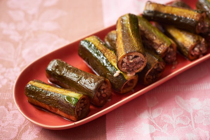 Zucchini mahshi on oblong red dish, atop pink and brown tablecloth.