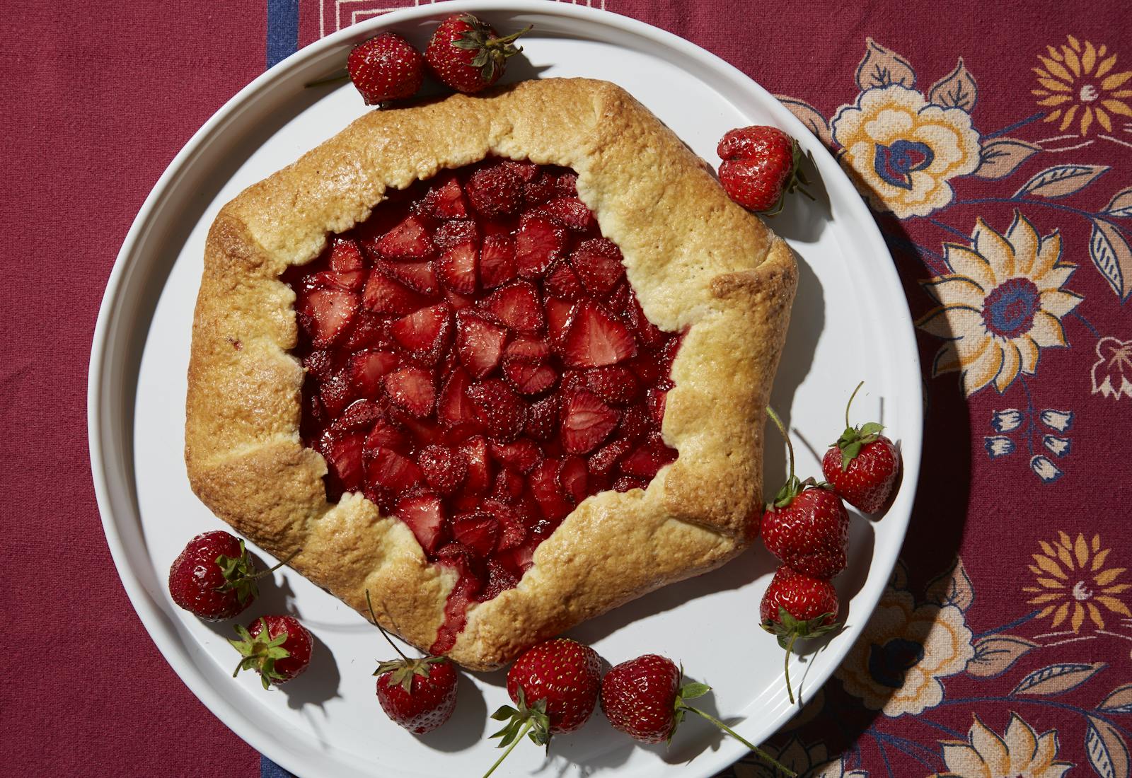 Strawberry galette on floral tablecloth.