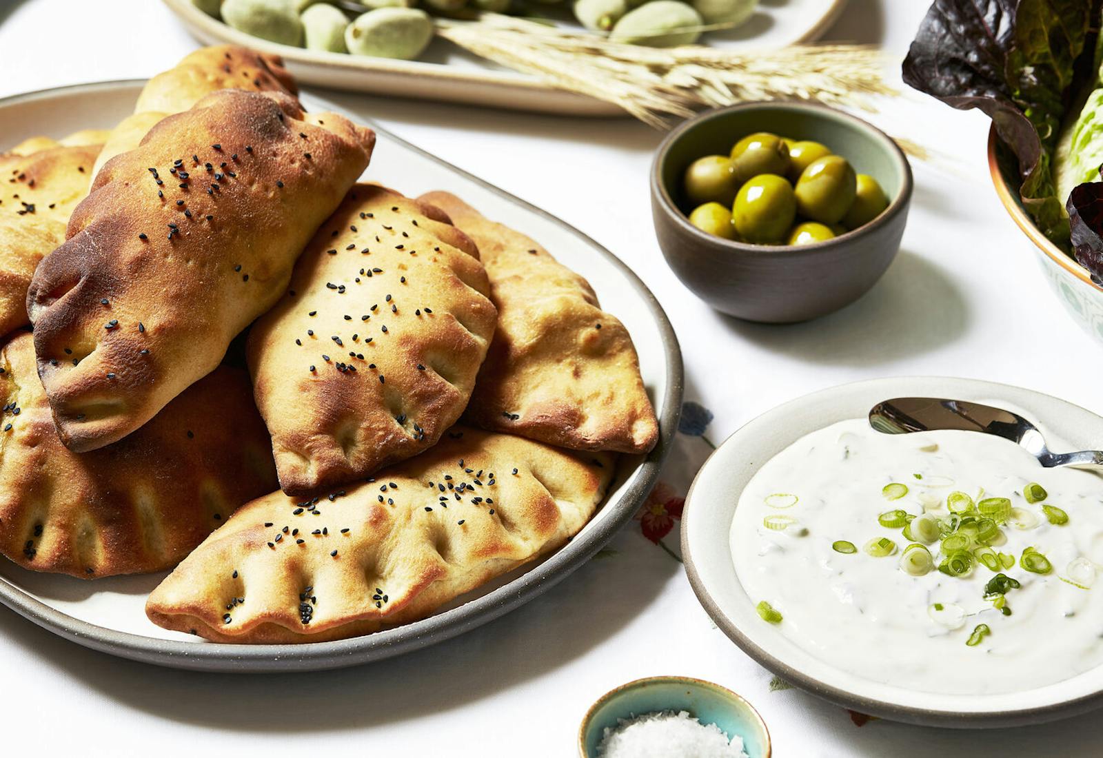 Kadeh with zizik, olives and purple lettuce atop white tablecloth.