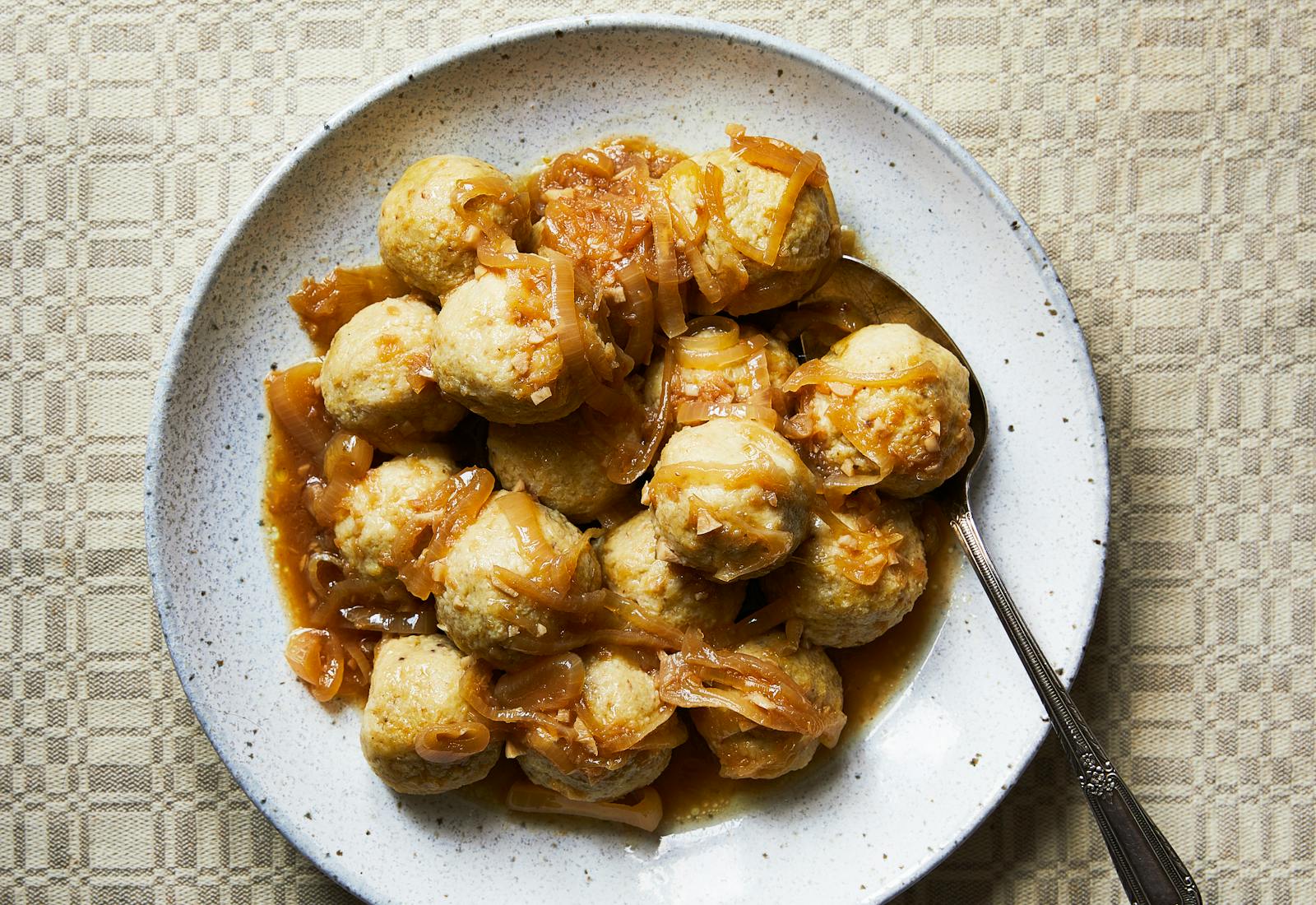 Kneidlach covered in Yassa sauce piled on serving plate.