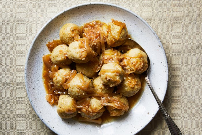 Kneidlach covered in Yassa sauce piled on serving plate.