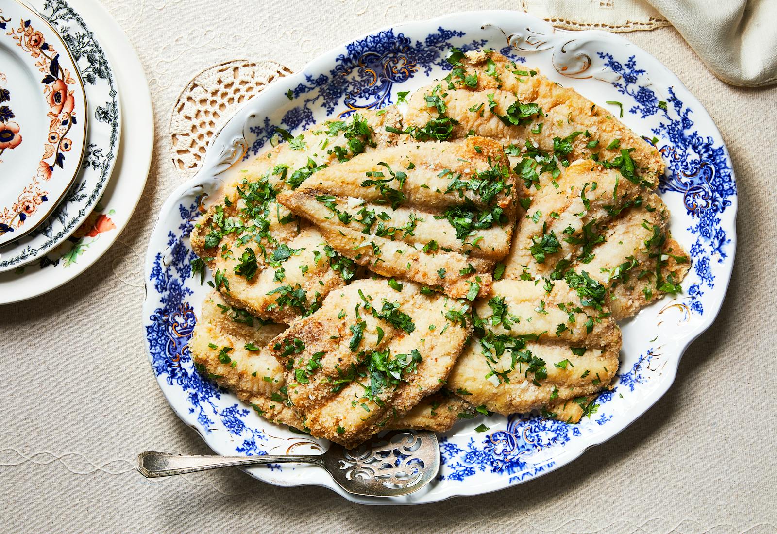 Fried whiting with cilantro and garlic on blue and white serving platter.