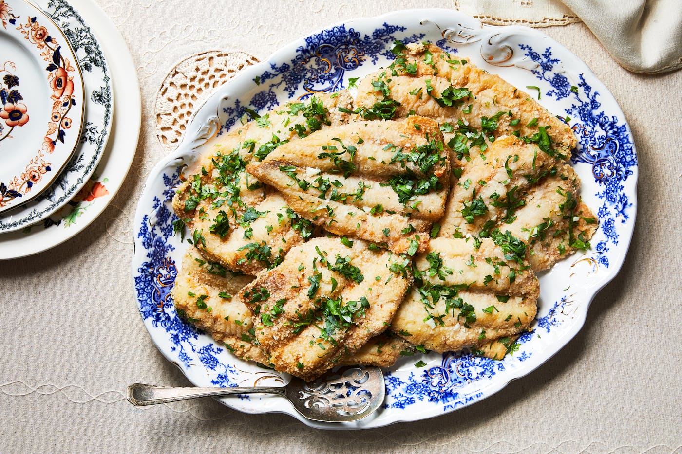 Fried whiting with cilantro and garlic on blue and white serving platter.