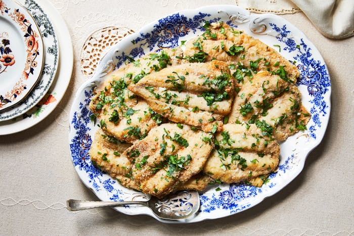 Fried whiting with cilantro and garlic on blue and white serving platter.