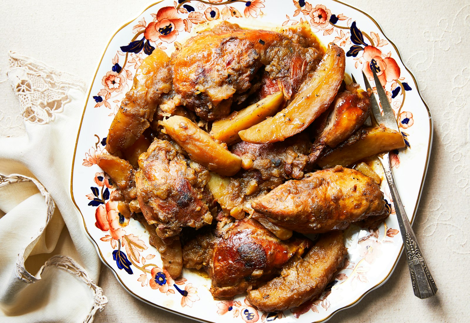 Bukharian chicken and potatoes on serving platter atop cream tablecloth.