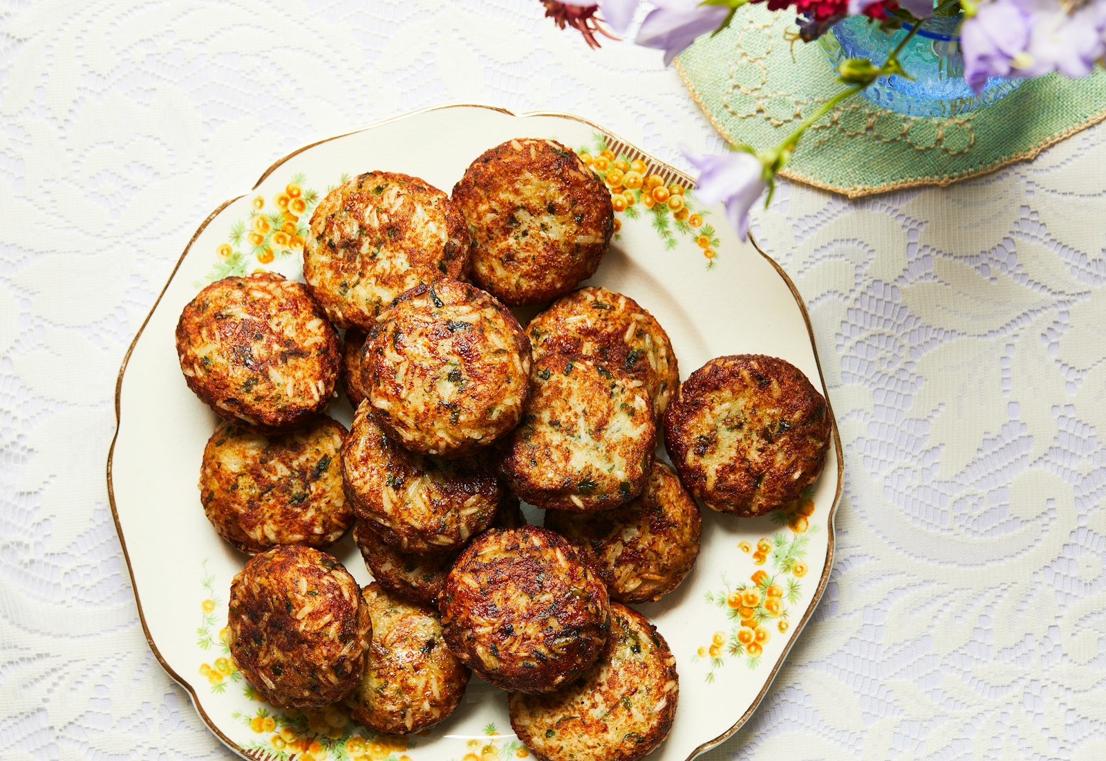 Fried arouk stacked on floral dinner plate atop white, lace tablecloth.