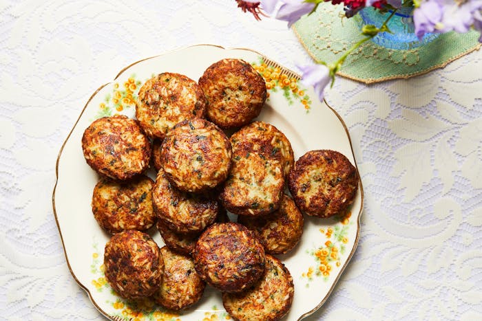 Fried arouk stacked on floral dinner plate atop white, lace tablecloth.