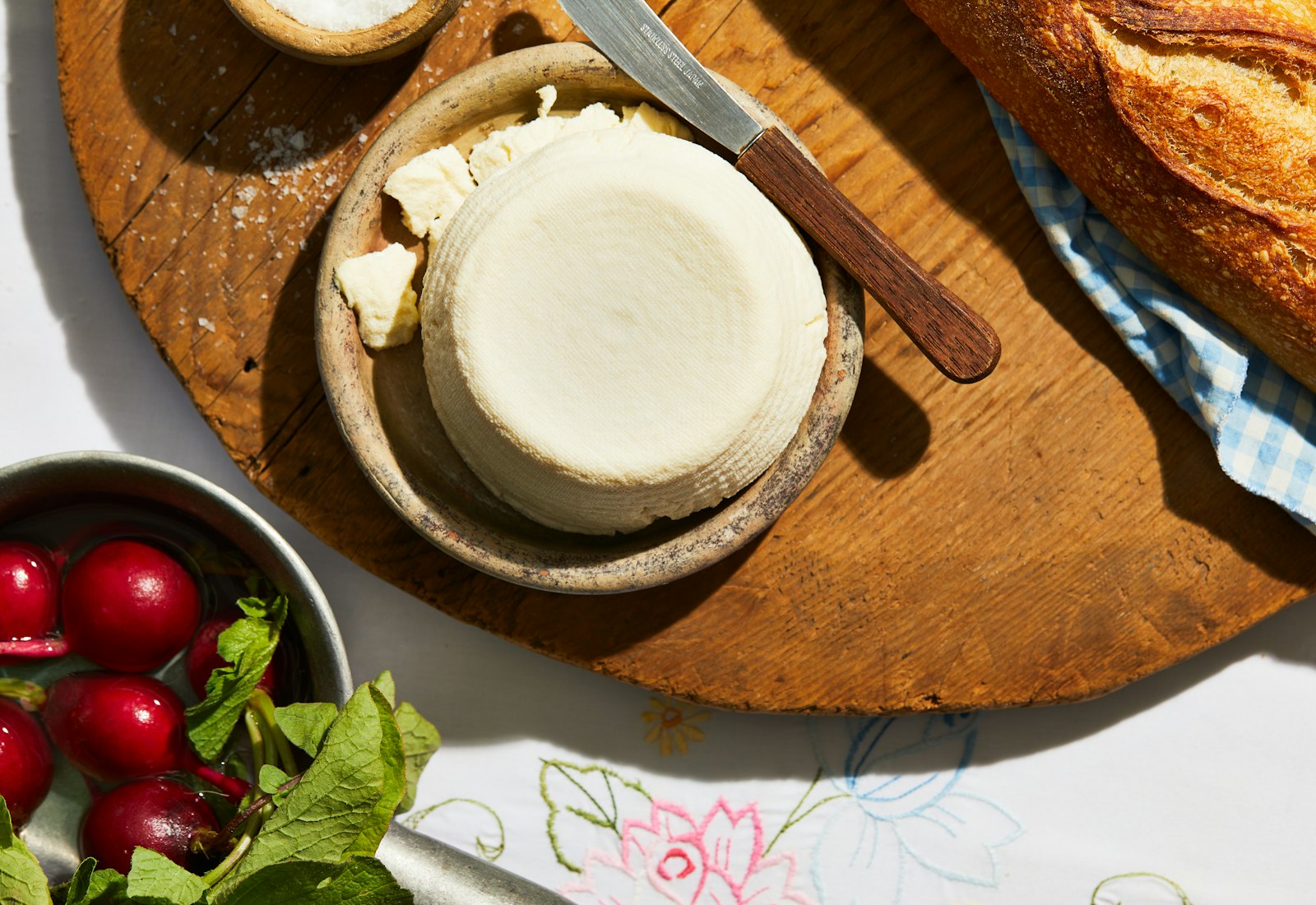 J'ben on small serving dish over wooden cutting board, next to radishes and baguette.